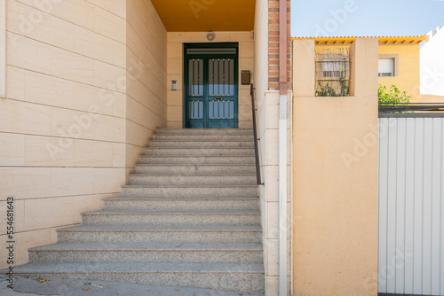 Entrance portal to a residential building with granite stairs, black metal railing and green painted front door