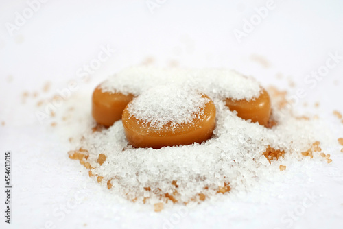 milk caramel candy and heap of sugar on white background