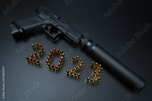 Stacked numbers from 9mm rounds 2023 year and a pistol with a silencer.