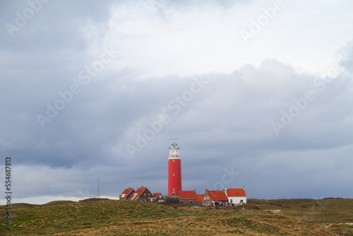 The lighthouse Eierland and some white houses with read tiled roofs in the dunes on the Dutch island Texel in the Wadden sea
