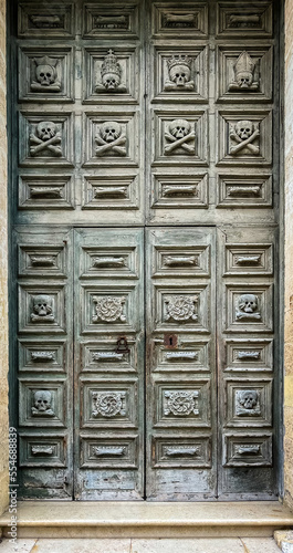 Old wooden door with skulls and crossbones carved into it at the entrance of the Church of the Purgatory in Matera in Basilicata in southern Italy