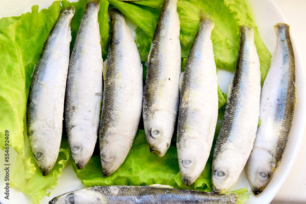 Frozen herring fish lies on lettuce leaves Frozen herring fish lies on lettuce leaves