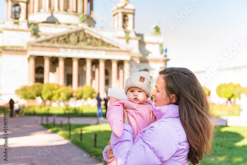 A young mother holds a small baby on St. Isaac's Square in St. Petersburg