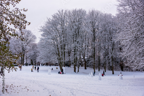 Kinder und Erwachsene haben Spaß in einem verschneiten Park im Dezember