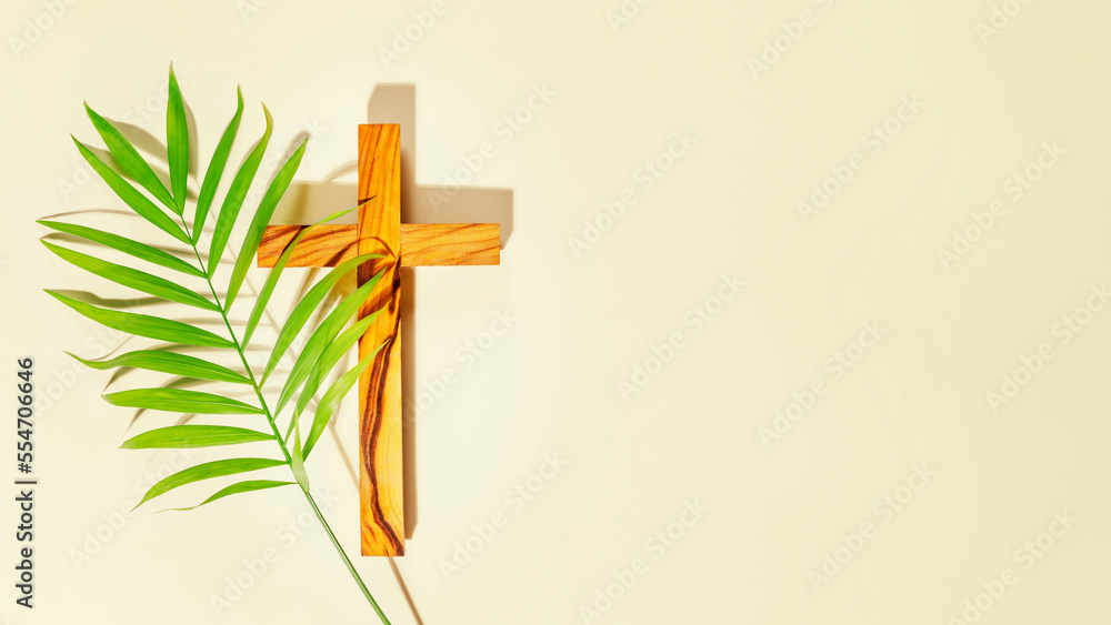 Palm Sunday Holiday. Wooden cross with palm leaf on light background