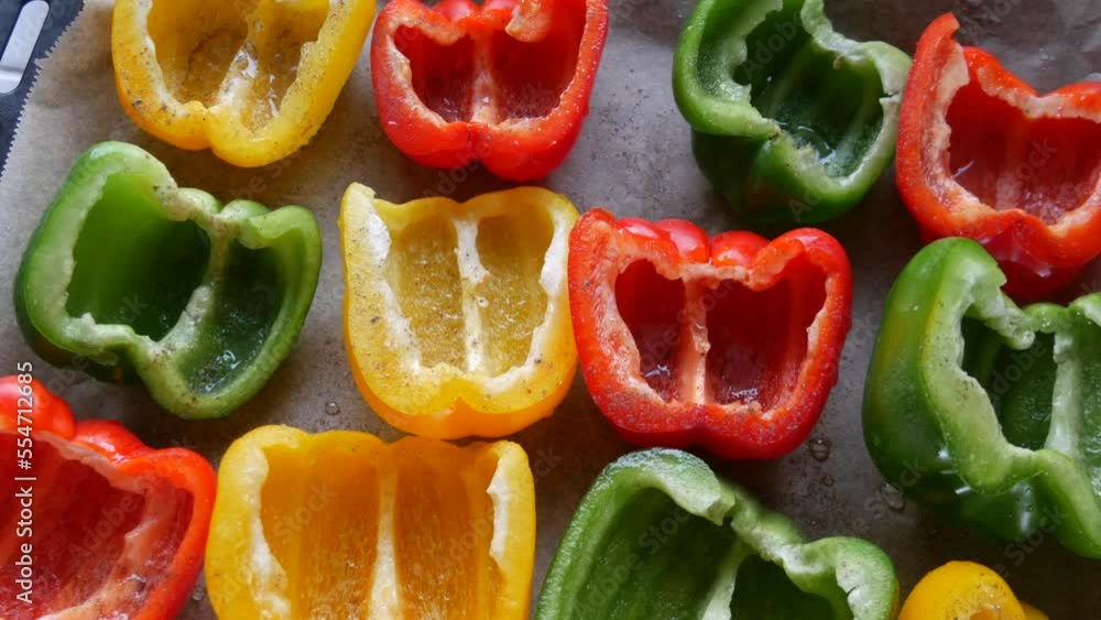Halves of yellow, red, green paprika pepper with spices and sunflower oil lie on a baking sheet parchment before baking Halves of yellow, red, green paprika pepper with spices and sunflower oil lie on a baking sheet parchment before baking