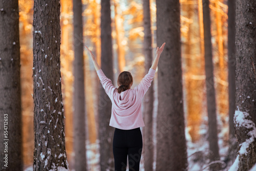 Kobieta medytująca o zachodzie słońca w zimowym lesie