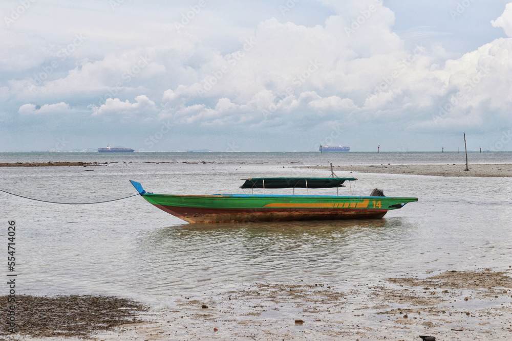 Obraz premium Small green river wooden motor boat for fishing and transporting tied up at the shallow sea.