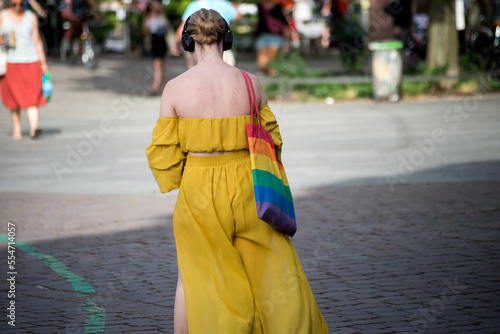 portrait on back view of lesbian girl with a rainbow bag walking in the street