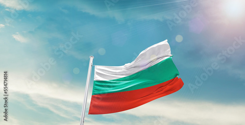 waving flag of Bulgaria in blue sky. the symbol of the state on wavy cotton fabric.