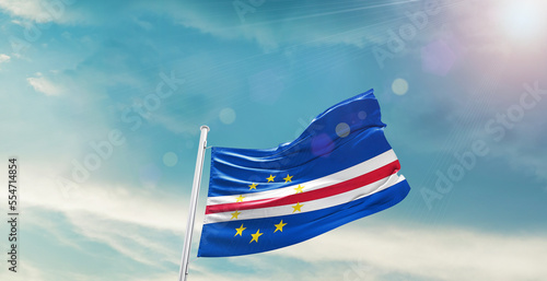 waving flag of Cabo Verde in blue sky. the symbol of the state on wavy cotton fabric.