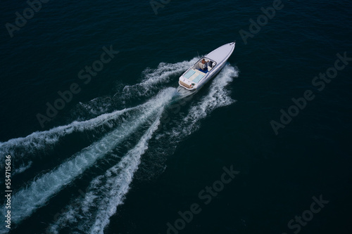 Speedboat with a man moving diagonally. White boat fast movement on dark water, white trail on the water. © Berg