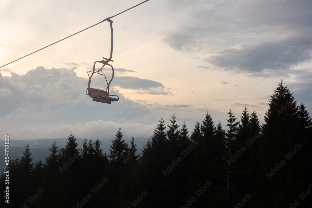 Chair lift in foreground, forrest and cloudy sky in background at evening. Chair lift in foreground, forrest and cloudy sky in background at evening.