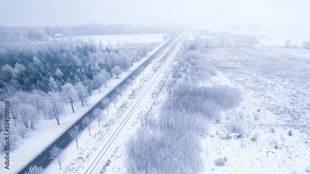 Winter landscape. Aerial view of the forest, white fields and asphalt road in a daylight. 