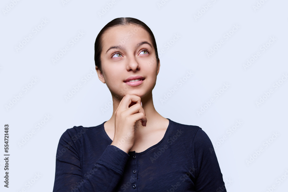 Pensive teenage female dreamily looking away, white studio background Pensive teenage female dreamily looking away, white studio background
