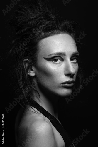 Fashion and make-up concept. Studio portrait of beautiful woman with eye shadows, long and dark dreadlocks hair looking at camera with seductive look. Black and white image