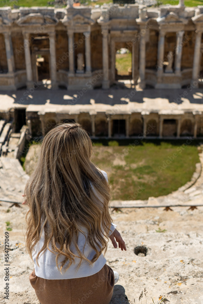 Rear view of blonde woman at Roman ruins of an ancient theatre 