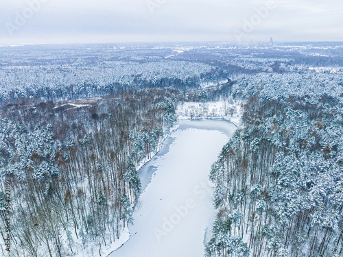 Aerial view of a frozen lake  a pond in the middle of the forest. The concept of a winter landscape  a beautiful view of a winter forest and a pond recorded from a drone.