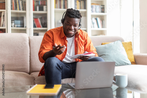 Cheerful african american man student attending webinar, using laptop © Prostock-studio