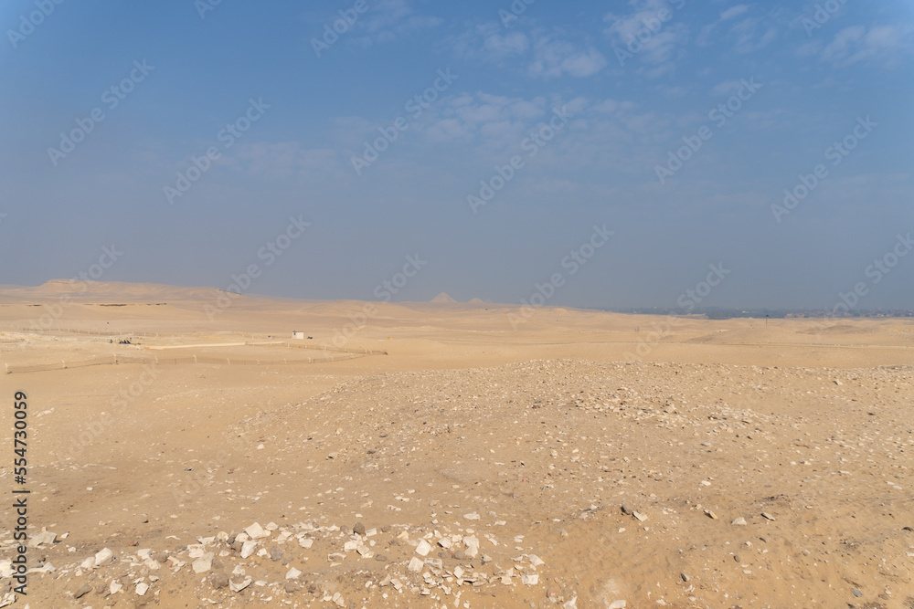 Giza pyramids seen in the distance, from the Sahara desert, on a sunny day with atmospheric pollution