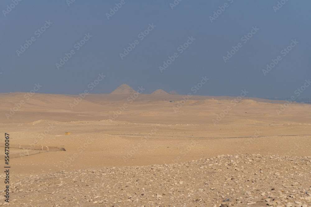 Giza pyramids seen in the distance, from the Sahara desert, on a sunny day with atmospheric pollution