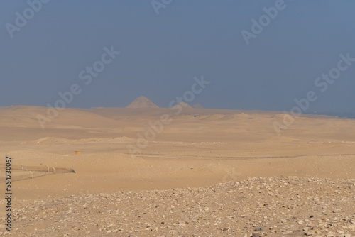 Giza pyramids seen in the distance, from the Sahara desert, on a sunny day with atmospheric pollution