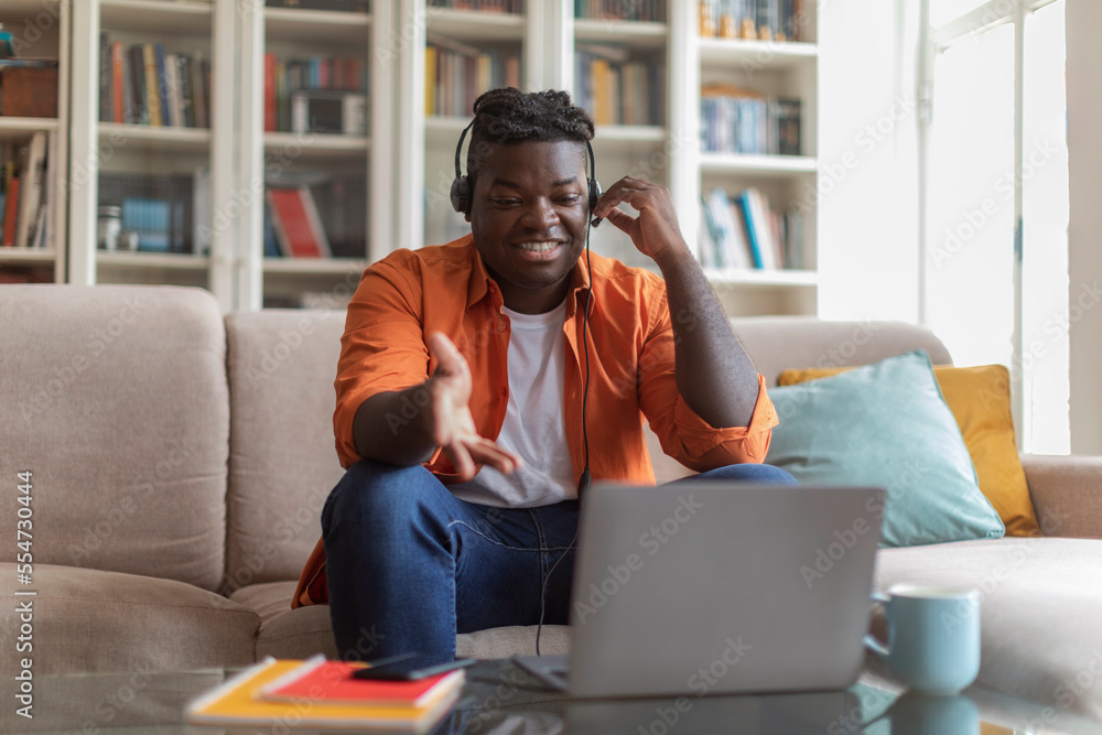 Happy millennial african american man student attending webinar, using laptop