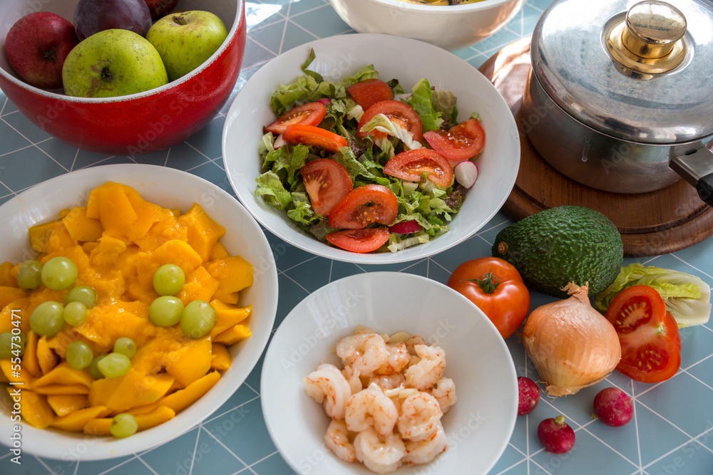 Platos de comida, condimentos y cacerola sobre una mesa de cocina