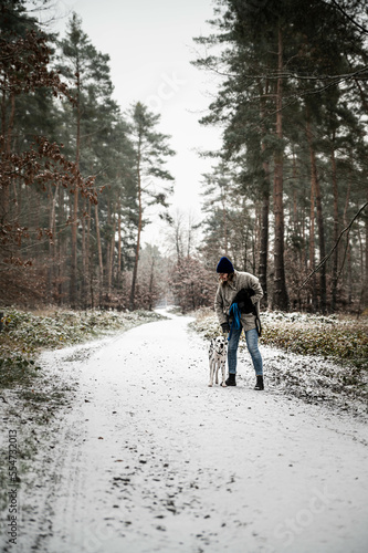 junge Frau arbeitet (Training) mit Hund (Dalmatiner) in verschneiten Wald im Winter