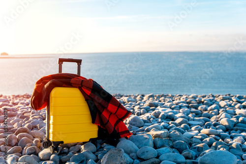 Yellow Suitcase with orange scarf on seaside. Travel concept. © Iryna