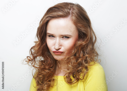 Pretty young woman with curly hair poses alone against white background.