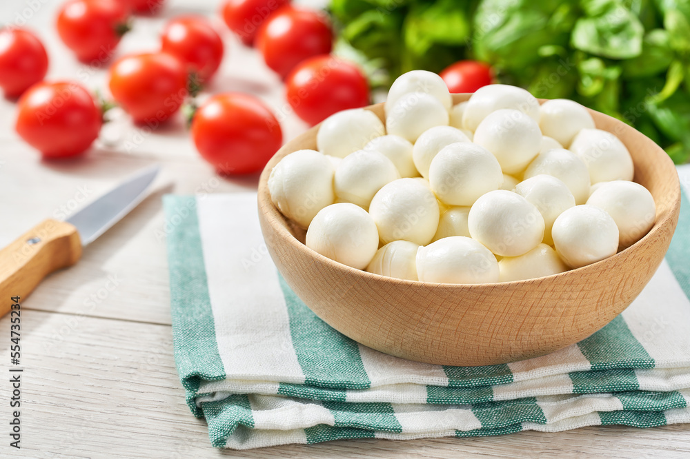 small balls of fresh white soft Italian mozzarella cheese, ripe red cherry tomatoes and fresh green basil herb, ready for making caprese salad. small balls of fresh white soft Italian mozzarella cheese, ripe red cherry tomatoes and fresh green basil herb, ready for making caprese salad.