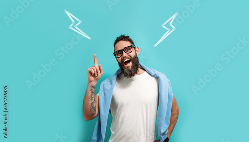 Photos Caucasian handsome man with a beard is isolated on a blue background, he having doubts and thinking how to find a way out of the current situation