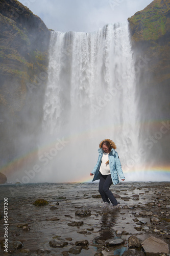 happy woman enjoying nature in iceland with a waterfall in the background