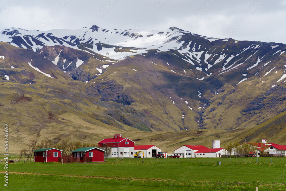 Red colored houses and snow capped mountains in iceland