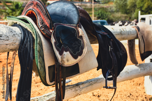 Traditional nomad horse saddle and rider equipments in the horse farm hanging on white fences waiting to be used