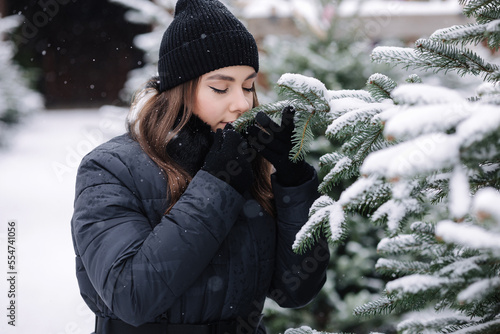 Attractive young woman choose Chrisstmas tree on outdoor trees farm. Woman smell fir tree photo