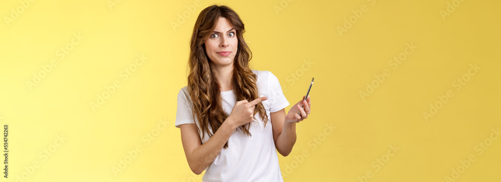 Girl answers strange weird call receive crazy upsetting message cringe doubtful displeased smirking dismay pointing suspicious smartphone stand yellow background intense frustrated - obrazy, fototapety, plakaty 