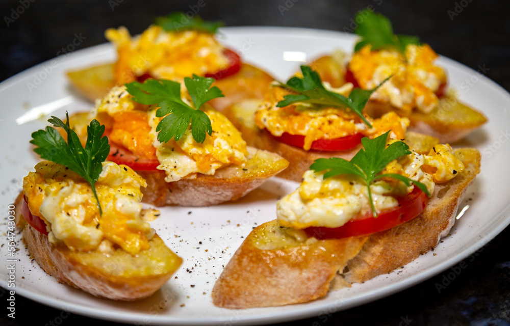 Bread with scrambled egg over ripe tomato and decorated with parsley leaf and black pepper gourmet Bread with scrambled egg over ripe tomato and decorated with parsley leaf and black pepper gourmet