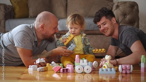 Authentic shot of young happy homosexual male gay family with adopted son toddler baby boyplay together