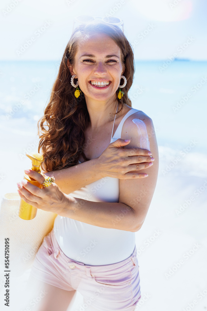 Portrait of happy stylish female in white beachwear at beach