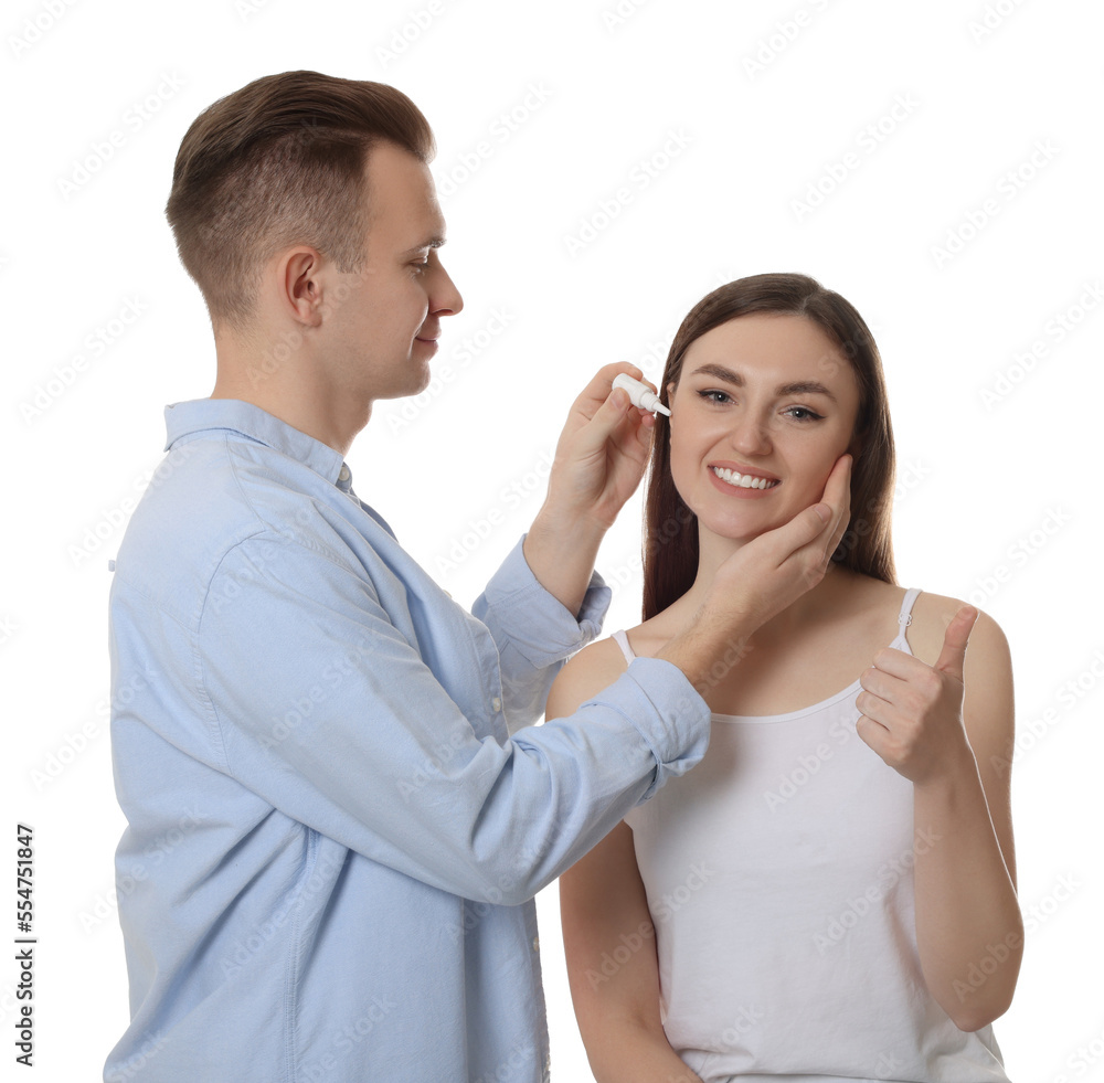 Man dripping medication into woman's ear on white background Man dripping medication into woman's ear on white background