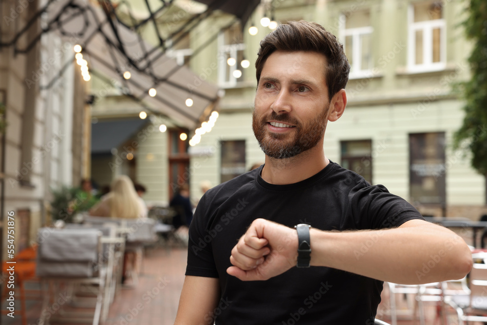 Handsome bearded man checking time in outdoor cafe Handsome bearded man checking time in outdoor cafe