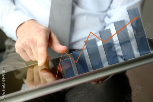 Businessman  analysis graphs on the tablet. Virtual chart shows growth.