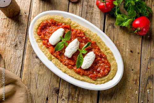 babaganoush dish on wooden table, eggplant paste with cheese and tomato paste on wooden table top view photo