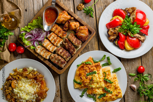 platter of different kebabs, pilaf with beeg, khachapuri with cheese, adjabsandali top view on wooden table