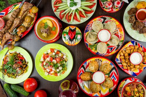 dishes of Uzbek cuisine lagman, pilaf, manti, kazan kebab, salad,skewers and shurpa top view photo