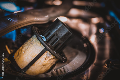 Food and grime coating a dishwasher filter that has been removed for maintenance and cleaning.  photo