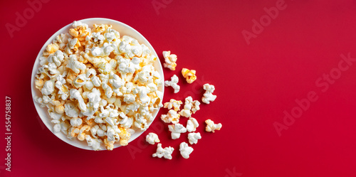 Scattered tasty cheese popcorn in bowl isolated on red background. Wallpaper, banner, header with copy space for text