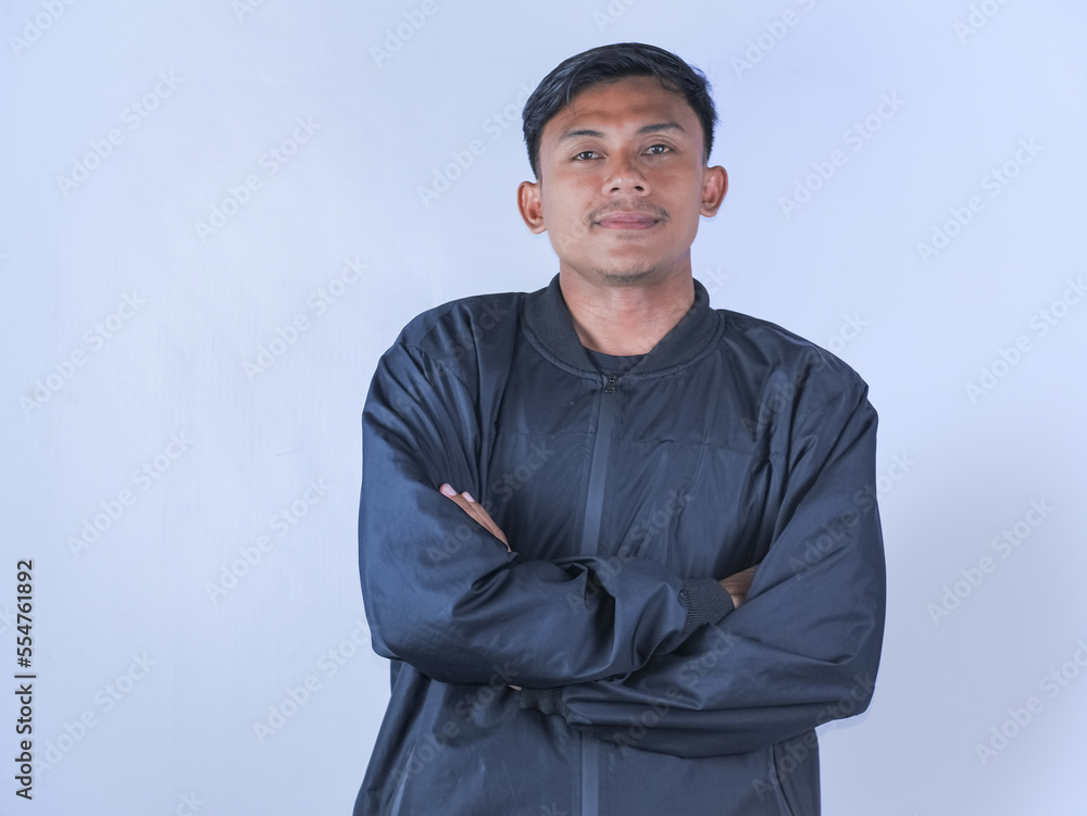 Confident person. Portrait of smiling asian man with folded arms looking at camera, wearing white shirt, posing isolated over orange studio background. Happy casual teenage male model laughing Confident person. Portrait of smiling asian man with folded arms looking at camera, wearing white shirt, posing isolated over orange studio background. Happy casual teenage male model laughing